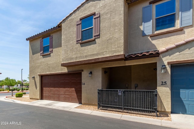 townhome / multi-family property with stucco siding, an attached garage, and a tile roof