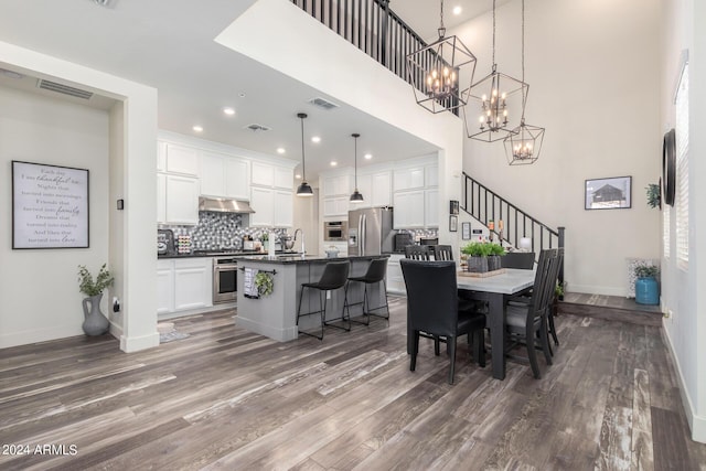dining area featuring visible vents, dark wood-style flooring, and a notable chandelier