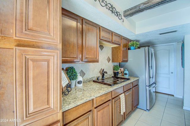 kitchen featuring sink, light stone countertops, a textured ceiling, light tile patterned floors, and tasteful backsplash