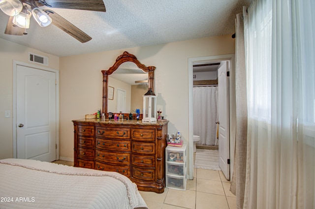 tiled bedroom with ceiling fan, a textured ceiling, and ensuite bath