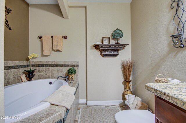 bathroom featuring vanity, tiled bath, and toilet