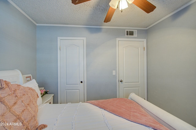 bedroom with ceiling fan, crown molding, and a textured ceiling