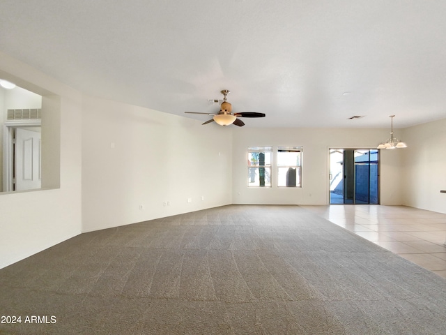 empty room with light tile patterned flooring and ceiling fan with notable chandelier