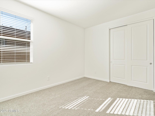 unfurnished bedroom featuring a closet and light colored carpet