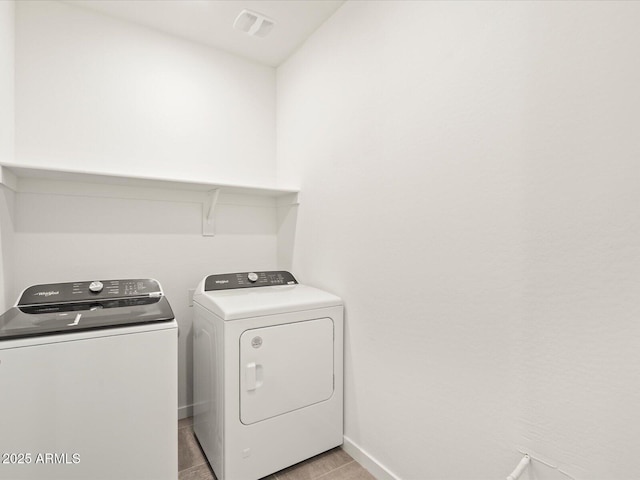 clothes washing area featuring washing machine and clothes dryer and light tile patterned flooring