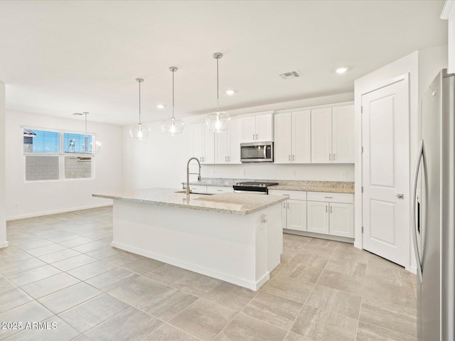 kitchen with stainless steel appliances, sink, decorative light fixtures, white cabinets, and an island with sink