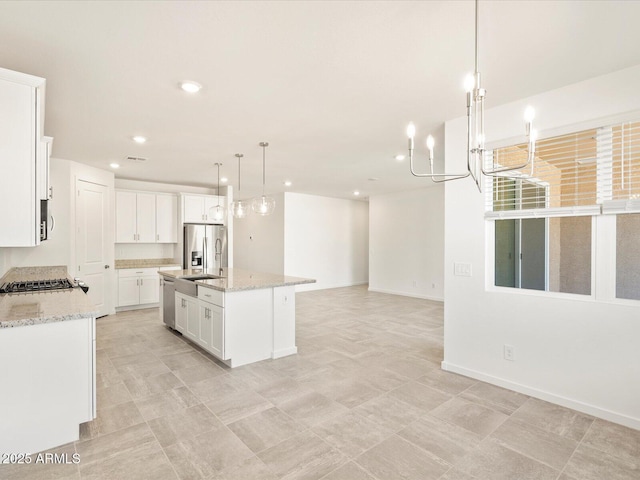 kitchen featuring light stone countertops, stainless steel refrigerator with ice dispenser, white cabinetry, hanging light fixtures, and an island with sink