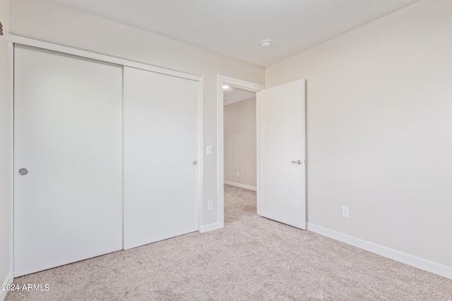 unfurnished bedroom featuring light carpet and a closet