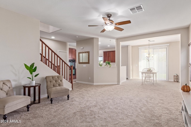 living area featuring light carpet and ceiling fan with notable chandelier