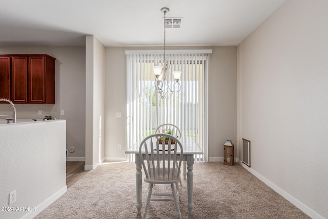 dining area with an inviting chandelier and light colored carpet