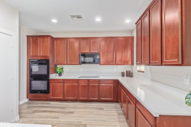 kitchen with light hardwood / wood-style flooring and black appliances