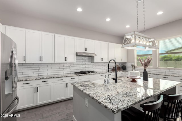 3938 E Appaloosa Rd, Gilbert, AZ 85296 - kitchen featuring appliances with stainless steel finishes, decorative backsplash, a sink, a kitchen bar, and an island with sink