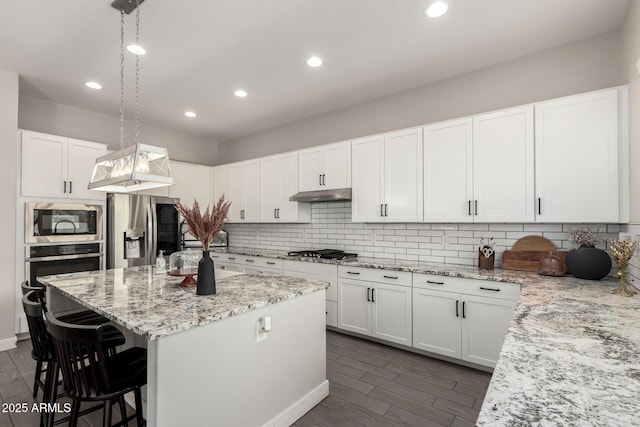3938 E Appaloosa Rd, Gilbert, AZ 85296 - kitchen featuring appliances with stainless steel finishes, a breakfast bar area, a center island, light stone counters, and decorative backsplash