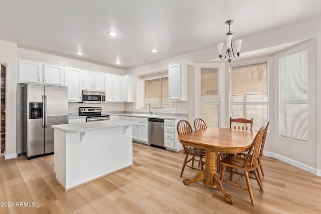 kitchen with a healthy amount of sunlight, light wood-type flooring, appliances with stainless steel finishes, and decorative light fixtures