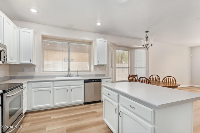 kitchen with appliances with stainless steel finishes, white cabinetry, light wood-type flooring, sink, and a chandelier