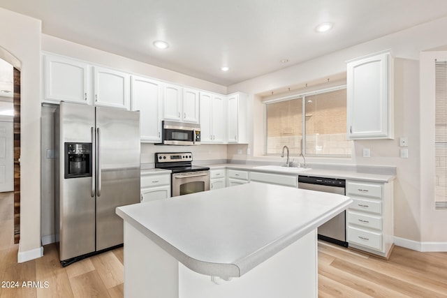 kitchen with white cabinets, sink, a kitchen island, stainless steel appliances, and light hardwood / wood-style floors