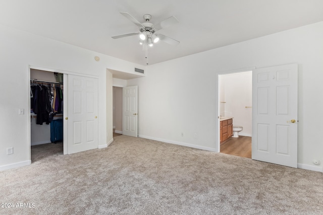 unfurnished bedroom with ensuite bathroom, ceiling fan, light colored carpet, and a closet