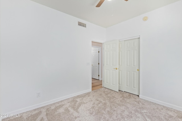 unfurnished bedroom with light carpet, a closet, and ceiling fan