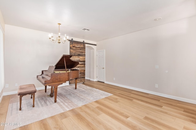 misc room featuring a barn door, light hardwood / wood-style flooring, and a notable chandelier