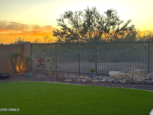 gate at dusk with fence and a yard