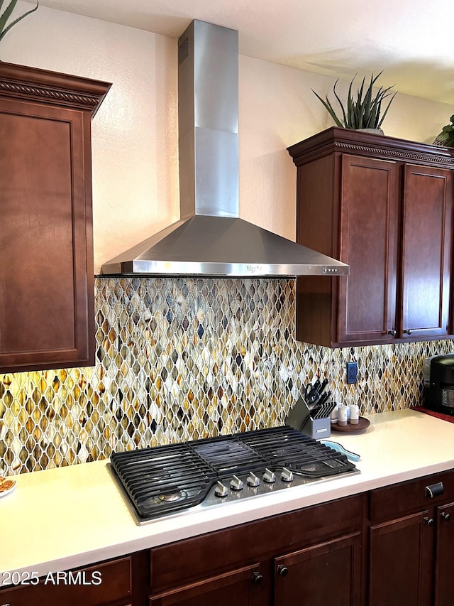 kitchen with stainless steel gas cooktop, light countertops, wall chimney range hood, and decorative backsplash