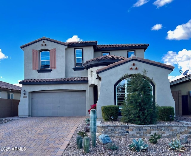 mediterranean / spanish home with a garage, decorative driveway, and stucco siding