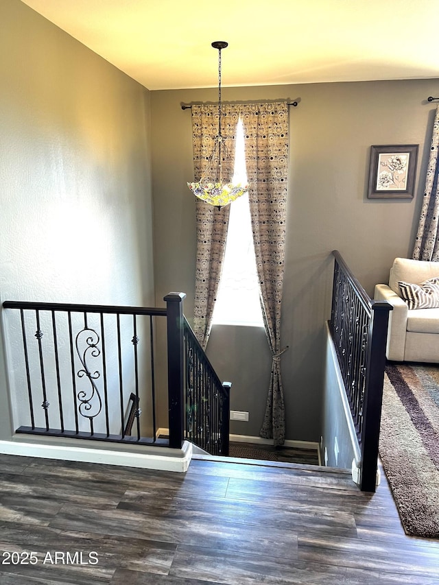 stairs featuring wood-type flooring and a notable chandelier