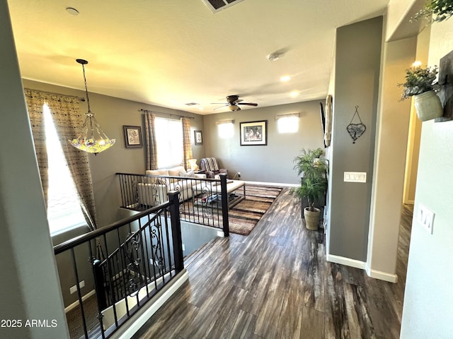 hall featuring baseboards, wood finished floors, and an upstairs landing