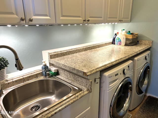 washroom featuring a textured wall, washer and clothes dryer, a sink, and cabinet space