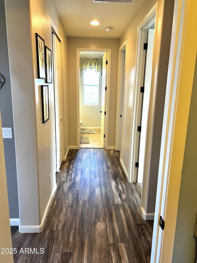 hall featuring dark wood-style flooring and baseboards