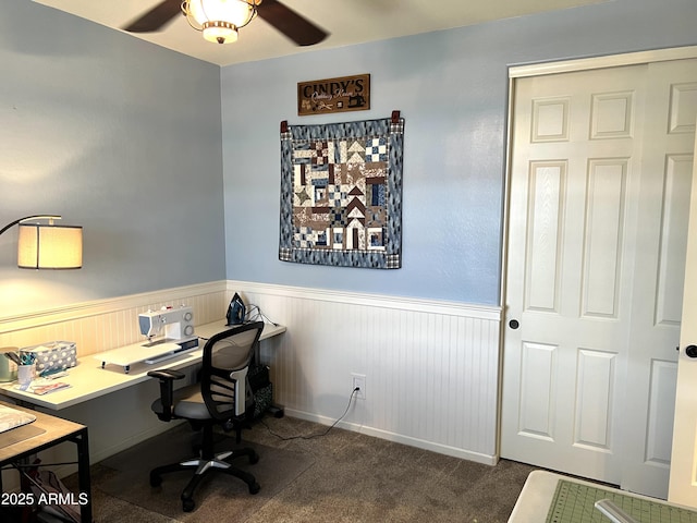 home office featuring a wainscoted wall, ceiling fan, and carpet flooring