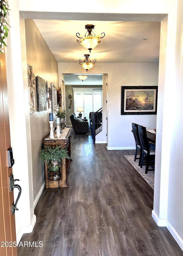 corridor with stairway, dark wood finished floors, and baseboards