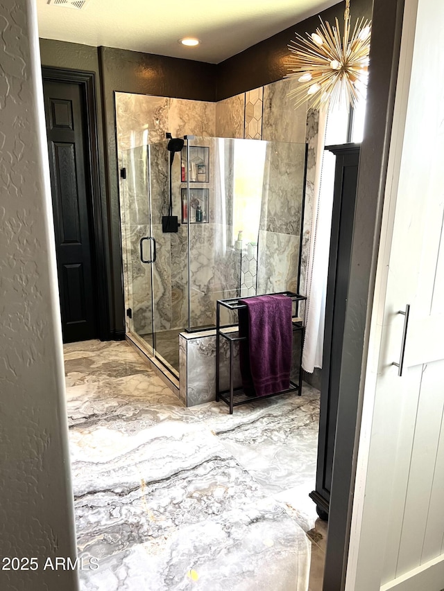 bathroom with marble finish floor, visible vents, a textured wall, and a shower stall