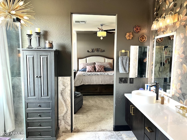 ensuite bathroom featuring a textured wall, vanity, visible vents, a ceiling fan, and ensuite bath