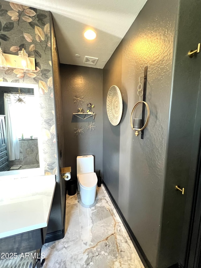 bathroom with visible vents, a textured wall, toilet, marble finish floor, and vanity