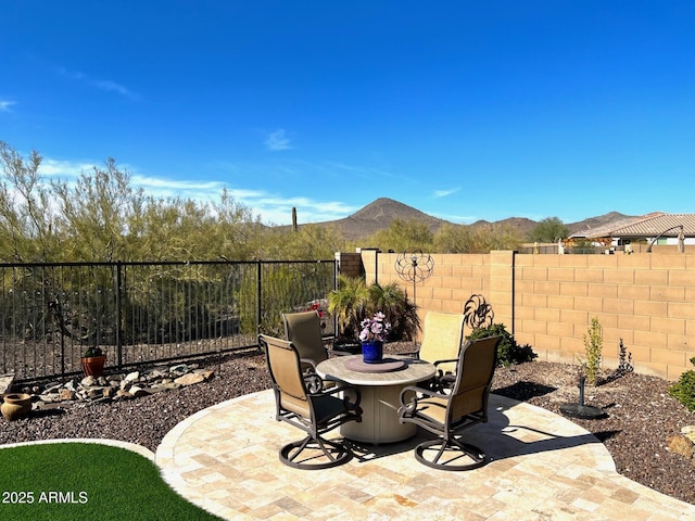 view of patio / terrace featuring outdoor dining space, a fenced backyard, and a mountain view