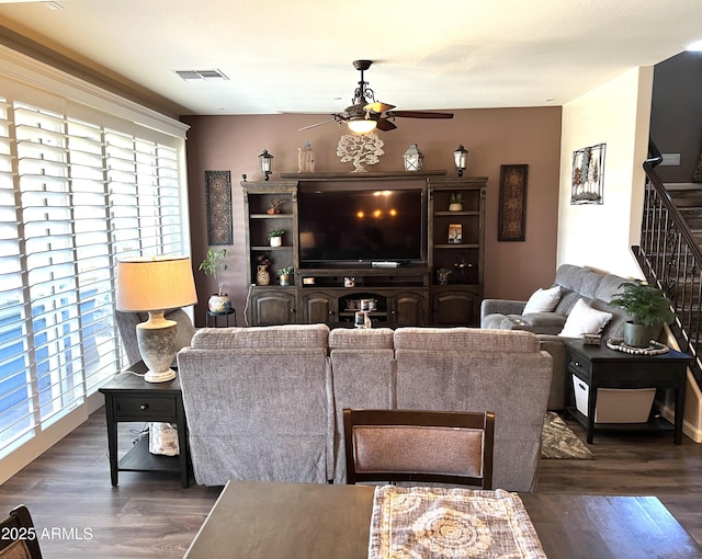 living area with stairs, wood finished floors, visible vents, and a ceiling fan