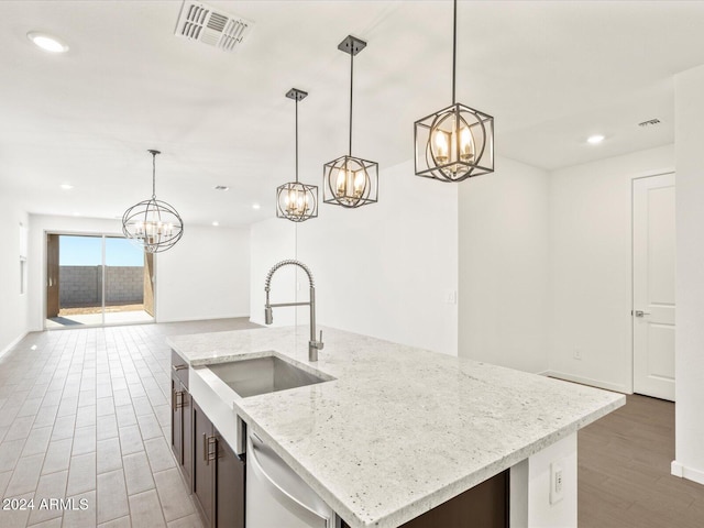 kitchen with a center island with sink, dark wood-type flooring, decorative light fixtures, and sink