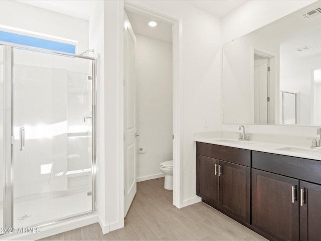 bathroom with wood-type flooring, vanity, toilet, and an enclosed shower