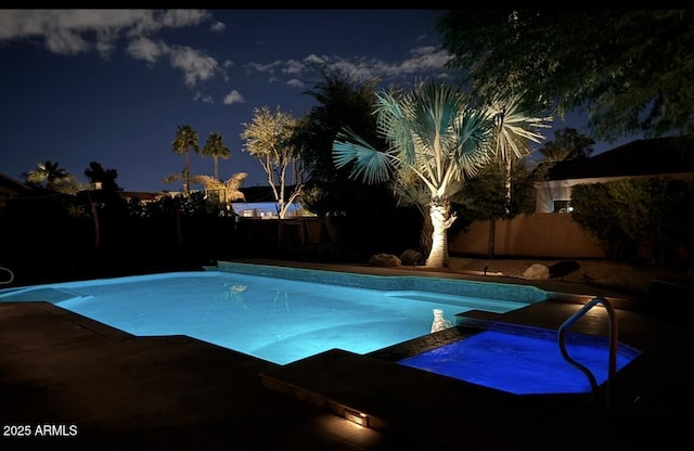 pool at twilight featuring an in ground hot tub