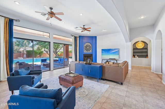 tiled living room featuring built in shelves and ceiling fan