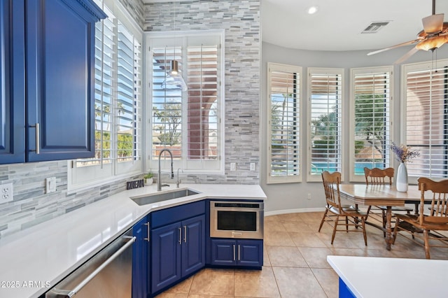 kitchen with blue cabinets, sink, tasteful backsplash, light tile patterned floors, and stainless steel appliances