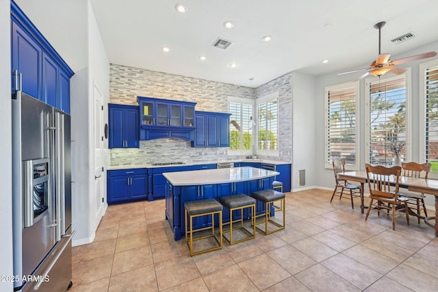 kitchen with decorative backsplash, a center island, gas cooktop, high end fridge, and blue cabinetry