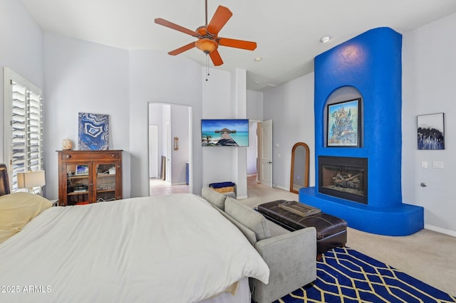 carpeted bedroom featuring a fireplace, ceiling fan, and a high ceiling