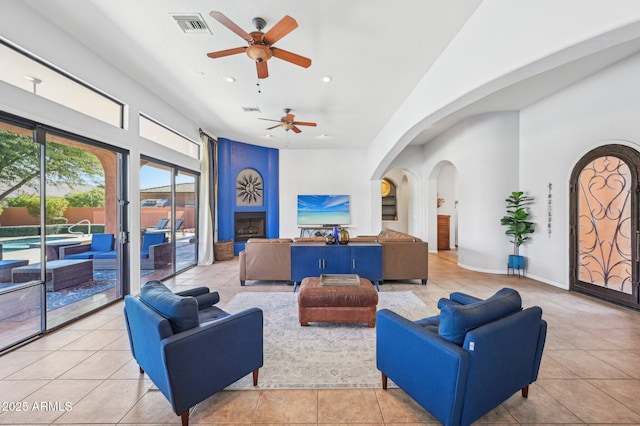 tiled living room with a fireplace and ceiling fan