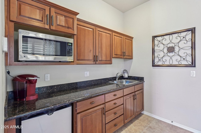 kitchen with sink, dark stone counters, and light tile patterned flooring