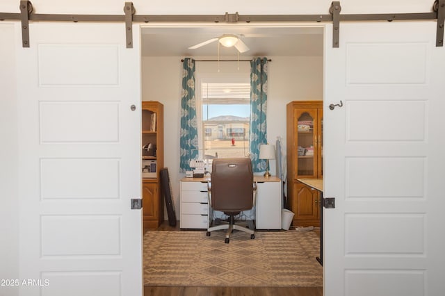 office with a barn door and dark wood finished floors
