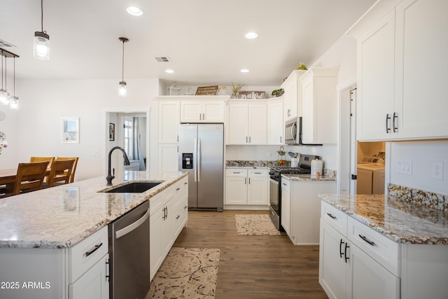kitchen featuring wood finished floors, appliances with stainless steel finishes, washing machine and dryer, visible vents, and a sink