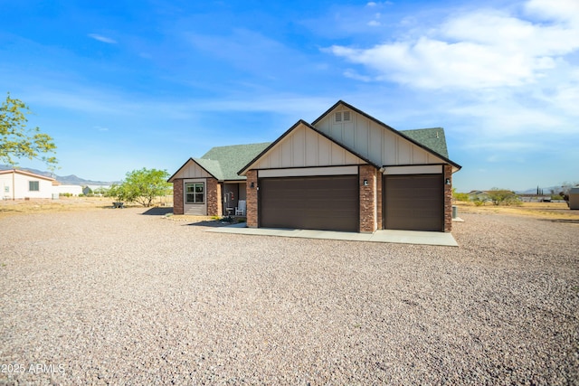 view of front facade with driveway, an attached garage, board and batten siding, and brick siding