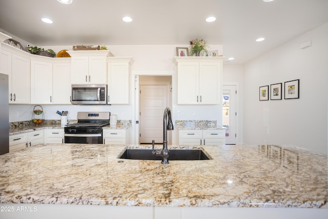 kitchen featuring recessed lighting, light stone countertops, a sink, and stainless steel appliances